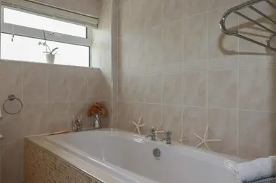 a white bath tub in a bathroom with a window at Coastman's Nest in Newquay