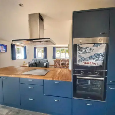 a kitchen with blue cabinets and a stove top oven at Heart of Kernow Holiday Home in Bugle