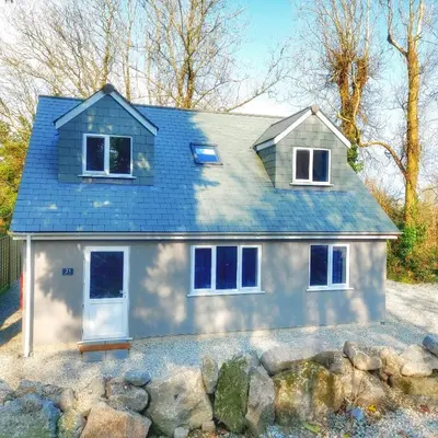 a white house with a blue roof at Heart of Kernow Holiday Home in Bugle