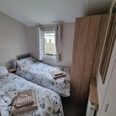 a small bedroom with two beds and a window at 7 Bays 6 Berth Willerby Molton Caravan in St Merryn