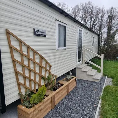 a tiny house with a staircase next to a building at 7 Bays 6 Berth Willerby Molton Caravan in St Merryn