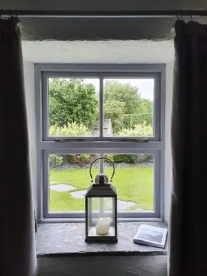 a candle in a lantern in front of a window at North Cornwall character cottage, sleeps 5, close to coast in Delabole