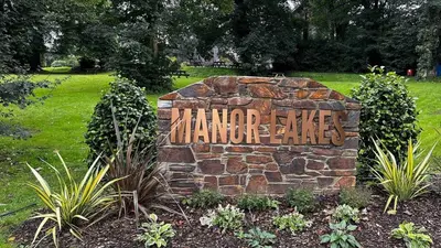 a sign on a stone wall in a park at Manor Lake Lodge Exclusive luxury lodge retreat in Saint Tudy