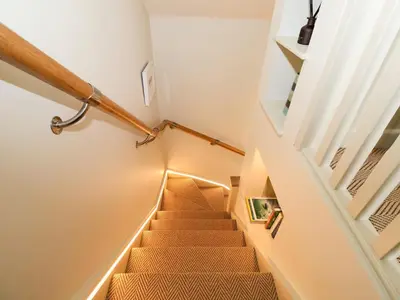 a staircase with white walls and wooden railings at The Cabin at Ropewalk in St. Agnes