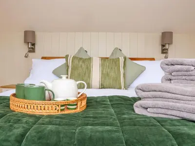 a bed with a tray with tea cups and towels at The Cabin at Ropewalk in St. Agnes