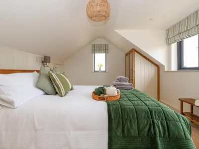 a bedroom with a white bed with a green blanket at The Cabin at Ropewalk in St. Agnes