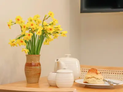 a table with a vase of flowers and a plate of bread at The Cabin at Ropewalk in St. Agnes