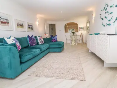 a living room with a green couch and a rug at Sandwaves in St Ives