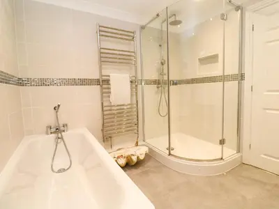 a white bathroom with a shower and a tub at Sandwaves in St Ives
