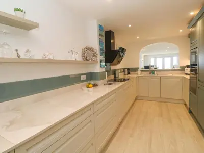 a large kitchen with white cabinets and a sink at Sandwaves in St Ives