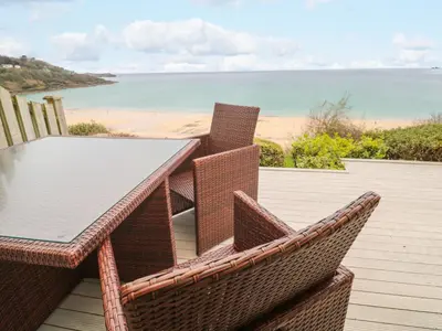 a table and chairs on a deck with a view of the beach at Sandwaves in St Ives