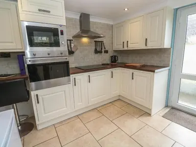 a kitchen with white cabinets and a stove top oven at Ty Metheven in Camborne