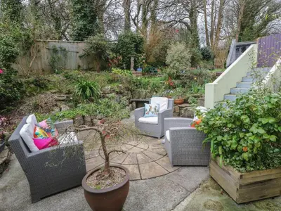 a garden with couches and chairs and a staircase at Ty Metheven in Camborne