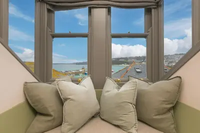 a couch with pillows in front of a window at She Sells Sanctuary in St Ives
