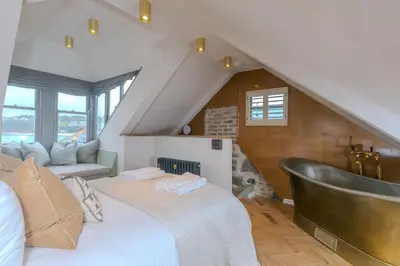 a attic bedroom with a bed and a bath tub at She Sells Sanctuary in St Ives