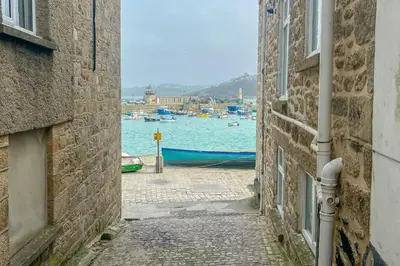 an alley between two buildings with a view of the water at She Sells Sanctuary in St Ives