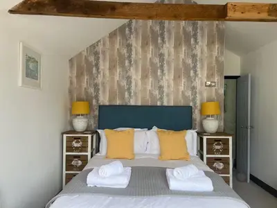 a bedroom with a large bed with yellow pillows at Beautiful Quayside Cottage Looe in Looe
