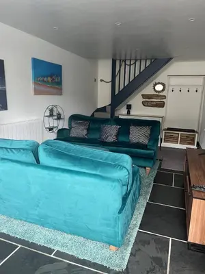 a living room with a blue couch and a staircase at Beautiful Quayside Cottage Looe in Looe