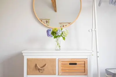 a table with a vase of flowers and a mirror at Beautiful Quayside Cottage Looe in Looe