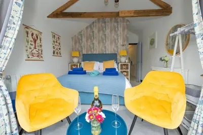 a bedroom with a bed and two yellow chairs at Beautiful Quayside Cottage Looe in Looe