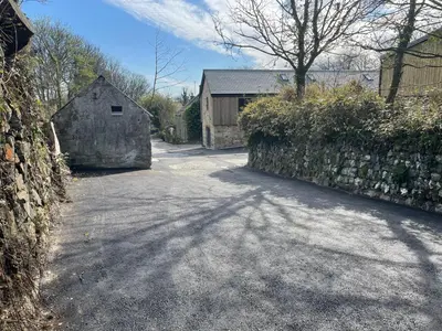 a driveway with a house and a fence and a building at Hednes Barn in Crowan