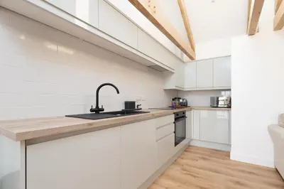 a kitchen with white cabinets and a sink at Hednes Barn in Crowan