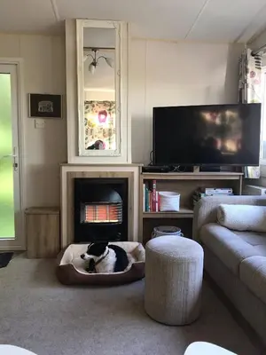 a living room with a dog bed in front of a fireplace at Badgers nestled in a cozy corner of the park in Wadebridge