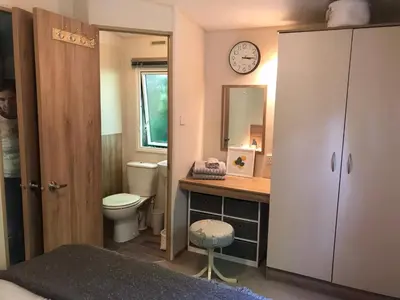 a bathroom with a toilet and a clock on the wall at Badgers nestled in a cozy corner of the park in Wadebridge