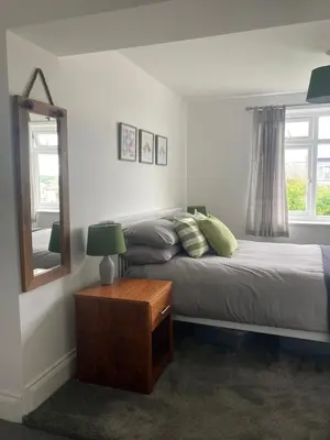 a bedroom with two beds and a mirror and a table at Newquay Beachcomber 2 Bedroom Apartment in Saint Columb Minor