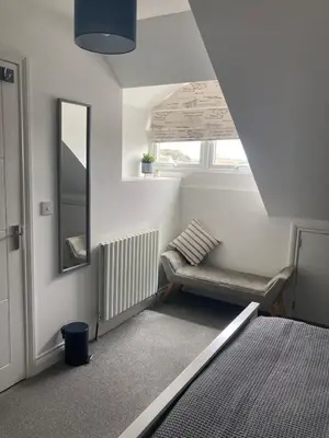 a room with a bench and a mirror and a window at Newquay Beachcomber 2 Bedroom Apartment in Saint Columb Minor