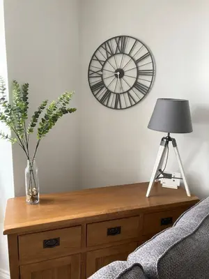 a table with a lamp and a clock on the wall at Newquay Beachcomber 2 Bedroom Apartment in Saint Columb Minor