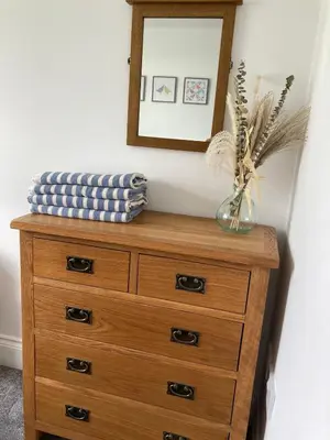 a wooden dresser with a mirror on top of it at Newquay Beachcomber 2 Bedroom Apartment in Saint Columb Minor
