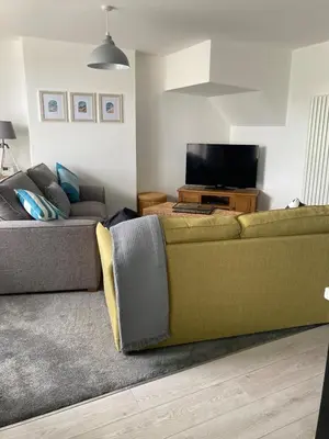 a living room with a green couch and a television at Newquay Beachcomber 2 Bedroom Apartment in Saint Columb Minor