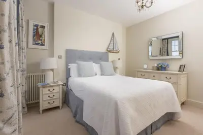a bedroom with a large bed with white sheets and a mirror at Dolly's Plaice, Fowey in Fowey