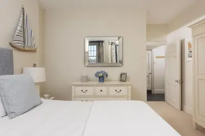 a bedroom with a white bed and a mirror at Dolly's Plaice, Fowey in Fowey