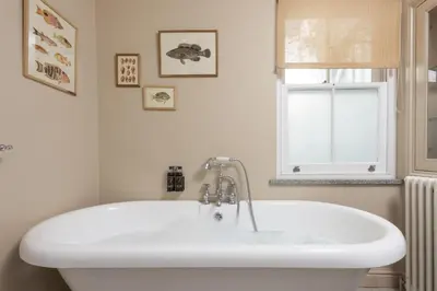 a white bath tub in a bathroom with a window at Dolly's Plaice, Fowey in Fowey