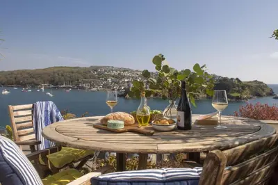 a wooden table with wine glasses and food on it at Dolly's Plaice, Fowey in Fowey