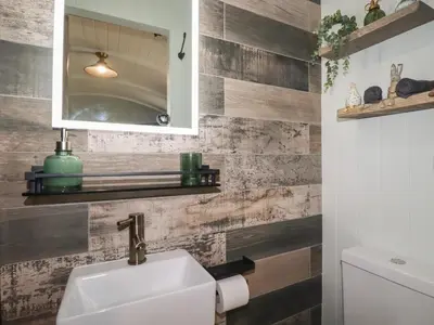 a bathroom with a white sink and wooden walls at The Highwood Hut in Liskeard