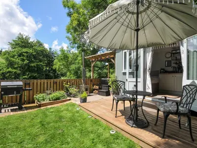 a patio with an umbrella and a table and chairs at The Highwood Hut in Liskeard