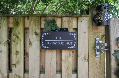 a sign on a wooden fence with a plant at The Highwood Hut in Liskeard