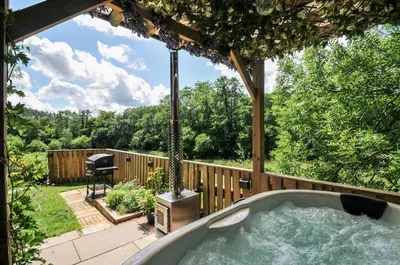 a hot tub in a backyard with a pergola at The Highwood Hut in Liskeard