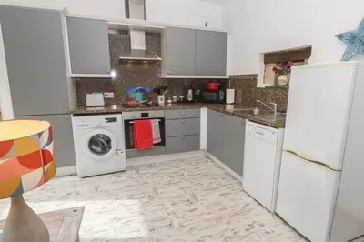 a kitchen with white cabinets and a washer and dryer at The Stable in Penzance
