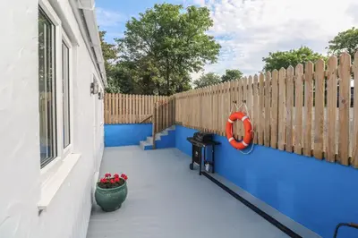 a patio with a blue wall and a fence at The Stable in Penzance