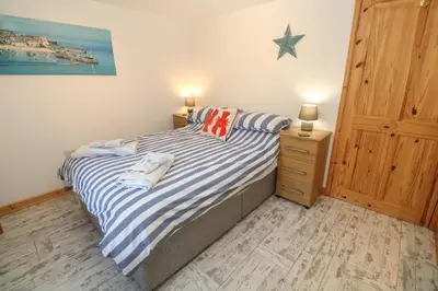 a bedroom with a bed with blue and white striped sheets at The Packing House in Penzance