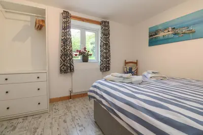 a bedroom with a bed and a dresser and a window at The Packing House in Penzance