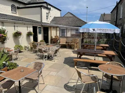 a patio with tables and chairs and an umbrella at Duke of Cornwall in St Austell