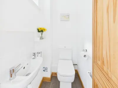 a white bathroom with a toilet and a sink at Surf View by Signature Stays - Pool - Beach Access in Crantock