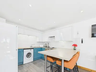 a kitchen with blue and white cabinets and a table at Surf View by Signature Stays - Pool - Beach Access in Crantock