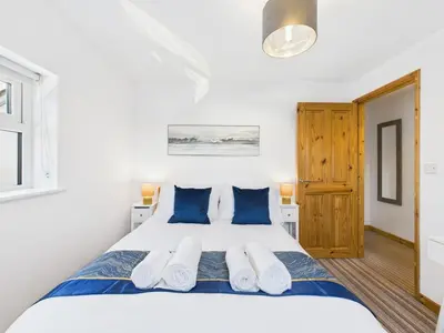 a bedroom with a large white bed with blue pillows at Surf View by Signature Stays - Pool - Beach Access in Crantock