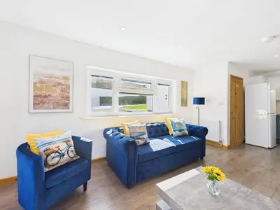 a living room with two blue couches and a table at Surf View by Signature Stays - Pool - Beach Access in Crantock